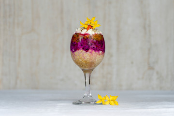 Fruit breakfast in a glass of oatmeal, red dragon fruit, passion fruit, mango and honey in white wooden background, closeup. The concept of healthy eating.