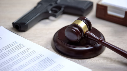 Gun on table, gavel lying on sound block, illegal use weapon, court hearing
