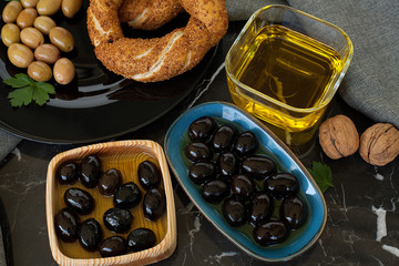 Olives and olives, olive oil on a beautiful stylish dishes, with Cutlery, on a dark background garlic, dill and fresh bread with cereals. The concept of olive products.