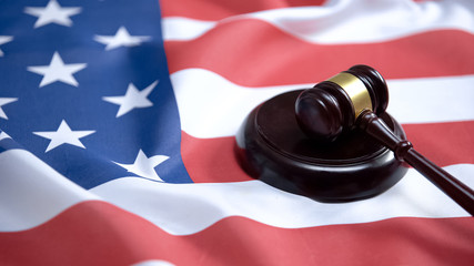Gavel striking on sound block against american flag, case law, court system - Powered by Adobe