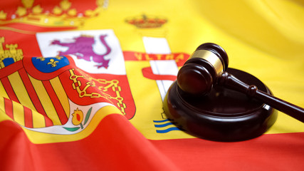 Gavel lying on sound block against Spanish flag, supreme court, legislation