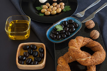 Olives and olives, olive oil on a beautiful stylish dishes, with Cutlery, on a dark background garlic, dill and fresh bread with cereals. The concept of olive products.