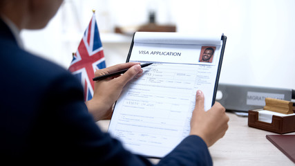 Female embassy worker checking visa application office, british flag, migration