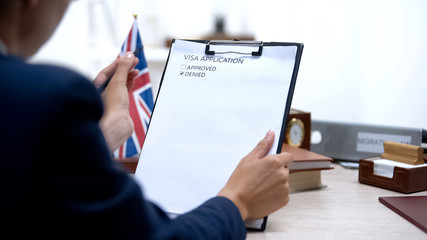 Embassy specialist denying visa application sitting office, british flag table