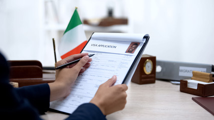 Female immigration inspector checking visa application office, italian flag