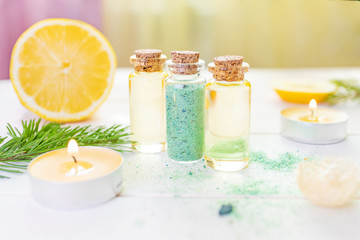 Fototapeta na wymiar The concept of aromatherapy, relaxation, organics. Transparent bottles with aromatic oil and sea salt, spruce branch, lemon, candles on a light wooden background. Organic Apothecary