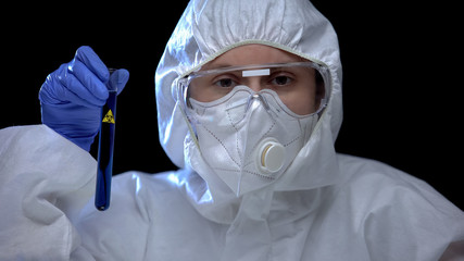 Worker of scientific lab holding test tube with biological hazard sign, harm