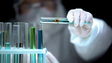 Lab assistant adding liquid from test tube with cross symbol, illegal research