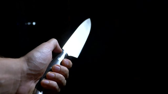 concept of halloween, violence. first-person view. male hand with a knife moves along a dark corridor