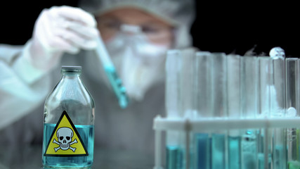 Laboratory scientist analyzing blue poisonous liquid, forbidden substances