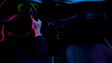 Man driving auto at night alone, round-the-clock taxi service, car interior