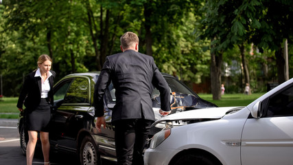 Naklejka premium Shocked man and woman looking at crashed cars on street, transport insurance