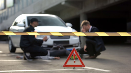 Warning tape front of policeman and driver at accident scene, safety on road