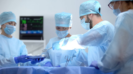 Assistant giving surgeon sterile medical equipment, invasive hospital operation