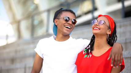 Fashionable teenagers in sunglasses hugging and laughing, modern youth, trends