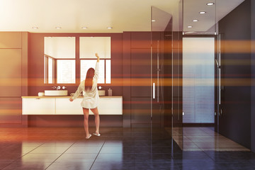 Woman in grey bathroom with shower and sink