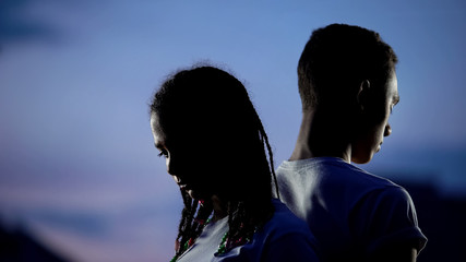 Upset teenagers standing back to back, forced separation, break-up concept