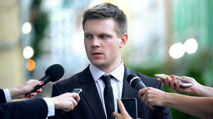Confused businessman giving interview on journalist press conference, reportage