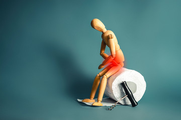 Wooden figure sit on a roll of toilet paper. Concept of the problem with digestion.