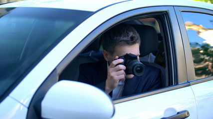 Fototapeta na wymiar Private detective spying from car, taking photos on camera, investigation