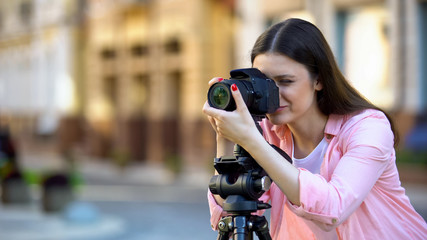 Professional female photographer focusing camera objective, photo shooting