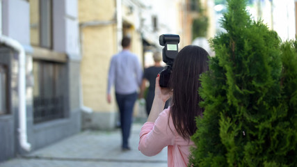 Yellow press journalist taking photo of elderly celebrity walking with young man