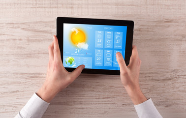 Man hand checking weekly weather forecast on tablet
