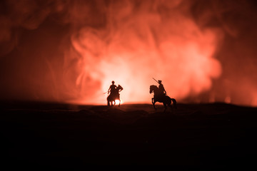 World war officer (or warrior) rider on horse with a sword ready to fight and soldiers on a dark foggy toned background. Battle scene battlefield of fighting soldiers.