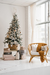 Christmas tree in the living room in bright colors, a chair from the rotunda near the floor-to-ceiling window