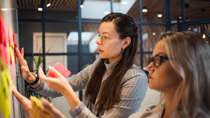 Teamwork, project management, agile methodology. Two young business women in the office