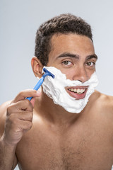 Handsome man beginning to shave his face