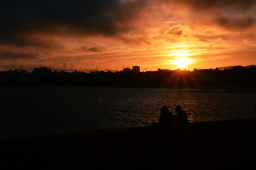Two people sitting on the grass at dusk.