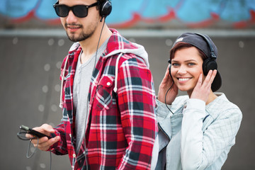 A young couple listening to a music outdoors