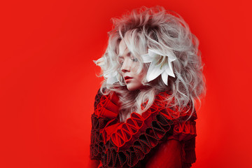 Shades of red. Strange attractive woman in a red outfit, on a red background, with lily flowers in...