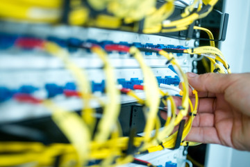 human hand fixing fiber glass cable into control panel