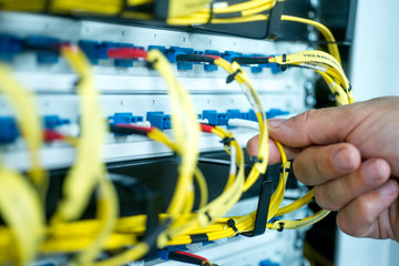 human hand fixing fiber glass cable into control panel