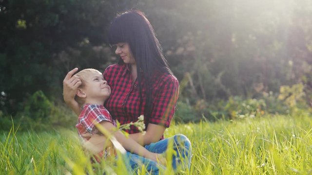 happy family mom and son concept . mom tender lifestyle childhood a video . slow motion video . mom brunette girl gently hugs takes care of the boy son blonde outdoors