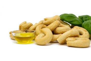 Italian taralli with olive oil and basil on a white background macro photography