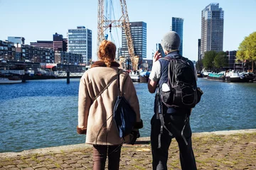 Rolgordijnen Young couple tourists looking and pointing to Rotterdam city harbour, future architecture concept, industrial lifestyle people © iordani
