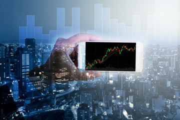 Businessman hold smartphone on trading graph and city background