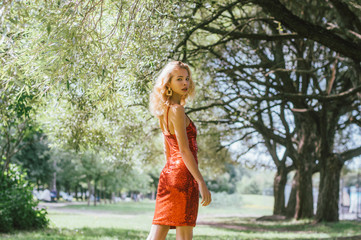 Portrait of beautiful girl in red short dress with sequins in park