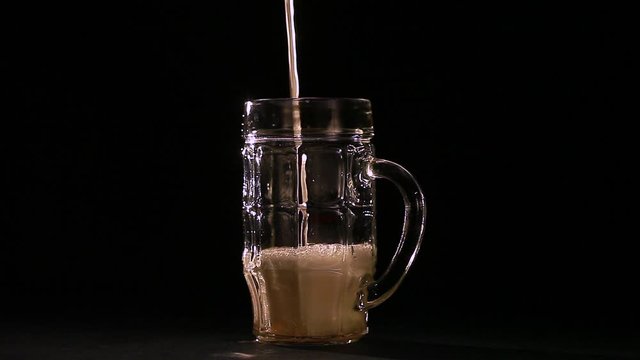 In a beer glass with a handle pour beer on a black background
