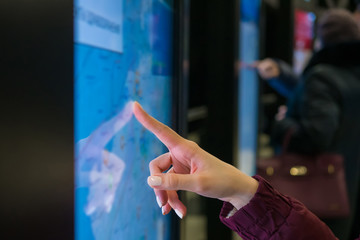Navigation, journey, sci-fi, technology concept. Woman hand using touchscreen display of kiosk with...