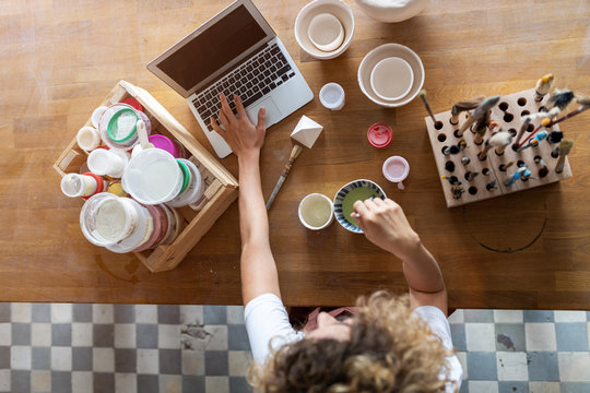 Woman pottery artist using laptop in art studio 
