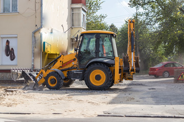 Obraz na płótnie Canvas Orange excavator on wheels works in the city