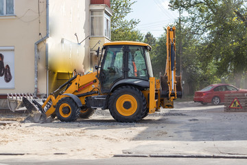 Obraz na płótnie Canvas Orange excavator on wheels works in the city