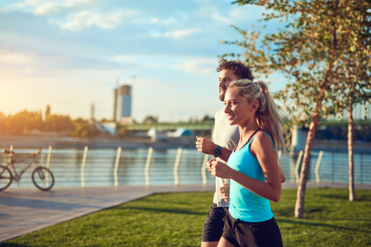 Modern woman and man jogging / exercising in urban surroundings near the river.