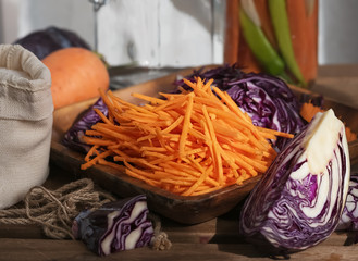 Sliced carrots and red cabbage on a wooden dish. Harvesting products. Kitchen. Fermented, canned vegetarian food. The concept of canned food. Close-up. Autumn. Horizontal frame.