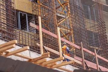 the concept of the construction process. Building under construction, with iron bars and one worker