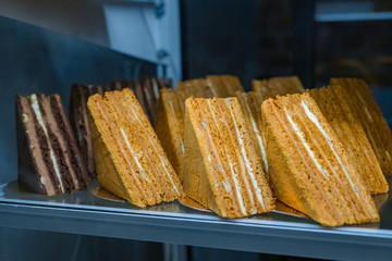 Assortment of delicious fresh layered chocolate and honey cake pieces with cream and nuts for sale on counter of shop, grocery, market, cafe or bakery. Dessert, sweet food and confectionery concept